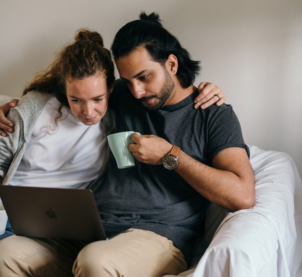 Photo of couple holding each other and looking at laptop